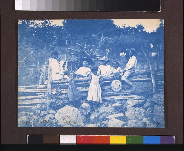 A photo of a family sitting on a log fence.