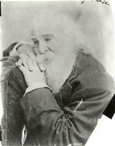 An aged black and white photo of Walt Whitman resting his head in his hands.