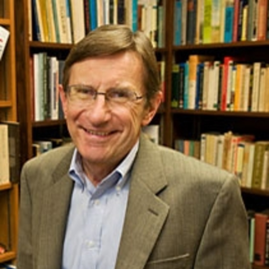 Ed Folsom stands in front of a shelf of books and smiles.